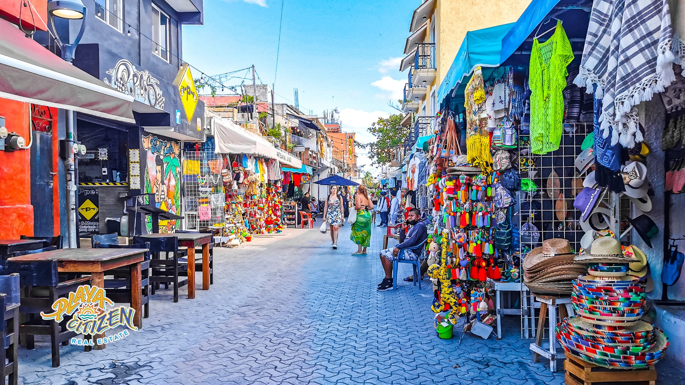 Expats and digital nomads walking down a street in Playa del Carmen lined with palm trees and apartment buildings, representing the best neighborhoods to live in the city.